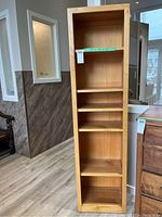 Front view of wood bookcase showing five shelves and visible wood grain.
