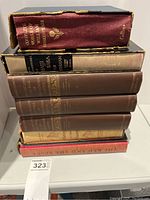 7 hardcover books stacked vertically including The Complete Works of William Shakespeare and The Adventures of Hajji Baba of Ispahan