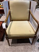 Front view of wooden chair with bamboo inspired detail and beige upholstery showing the seat cushion stain.