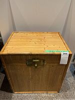 Front and top side view of the bamboo look chest showing the natural bamboo pattern and brass latch lock on the front with a framed top edge.