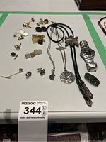 Overview of watch, necklaces, cufflinks and tie clips on table