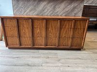 Front view of long low dresser showing six front drawers with vertical fluted handles and medium brown walnut veneer