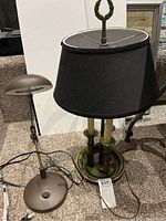 Two lights shown together: a metal adjustable desk lamp with round base and a table lamp with black fabric lampshade and green base.