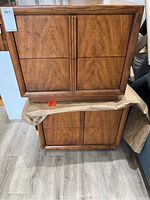 Two stacked walnut veneer nightstands showing front drawer panels and frame