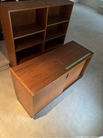 Two-piece wood cabinet and bookcase hutch, top hutch separated from base