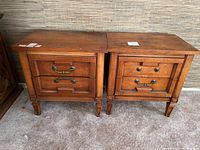 Two wooden nightstands side by side with brass handles and carved wooden detailing.