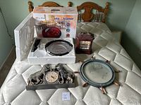 Photo showing the automatic floor vacuum cleaner in its white styrofoam packaging along with two decorative clocks and a round mirror placed on a mattress.