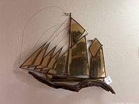 Full view of bronze and brass ship sculpture on wall, showing sails and base