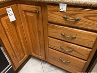 Photo of oak wood kitchen cabinet and four drawers showing exterior and drawer handles