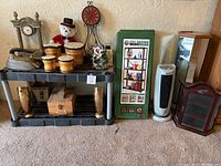 Photo showing a variety of decor items including clocks, bear, decorative drums, iron, shelving boxes, and vases arranged on and near plastic shelving.