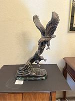 Bronze eagle statue showing two eagles with wings spread atop a green marble base on dark surface.
