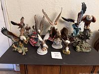 Photo showing multiple eagle statues grouped on a black surface against wall backdrop.