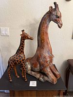 Both giraffe statues displayed side by side on a black surface