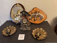 Front view of all items: framed unicorn mirror, horse clock, wood horse plaque, pair of brass candle holders.