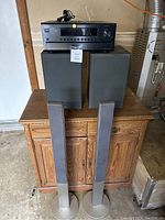 Onkyo AV receiver with two Yamaha bookshelf speakers on wooden cabinet, two tall floor speakers in front