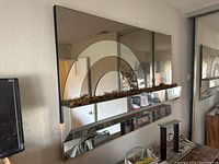 Front view of rectangular wall mirror with three concentric arch designs and integrated shelf containing dried moss, mirrored top and bottom sections