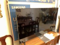 Samsung 50 inch TV in front of original box, showing the TV screen and stand.