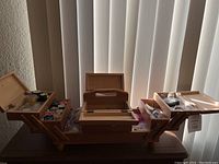 Overall view of the wooden sewing box fully opened showing multiple compartments with sewing supplies inside.