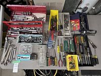 Wide angle photo showing all tools laid out on a table with toolboxes, wrenches, screwdrivers, sockets, and pliers visible