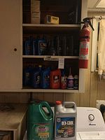 Shelf with various motor oil containers and automotive fluids including Chevron, Valvoline, DEX-COOL container, green Valvoline GTX jug, and red Petro-Canada container.