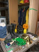 Full view of safety gear lot on table showing helmets, boots, gloves, caution light, and various protective glasses