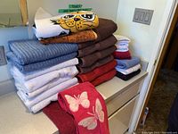 Stack of assorted folded towels including bath and hand towels in various colors and designs on countertop.