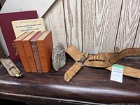 Four vintage Zane Grey books, two Canadian nautical charts, rock, and leather hunting belt with leather sleeve arranged on wooden surface.