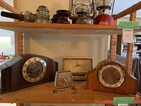 Photo of four vintage clocks on wooden shelves showing mantel clocks and smaller sizes