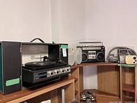 Philco portable record player stereo on wooden shelf along with Sears cassette player and small radios