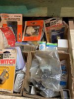 Image showing assorted electrical parts in original packaging including circuit tester, switches, sockets, and push button cover.