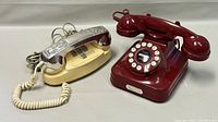 Two vintage phones side by side: Northern Telecom Princess red phone and cream Birks Rideau phone with chrome handle.