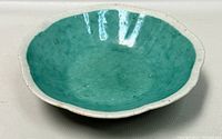 Top view of antique Chinese ceramic bowl with turquoise/aqua blue glaze inside and scalloped edges.