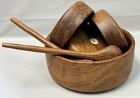 Large round wooden salad bowl, three matching smaller bowls, one extra small bowl, and wooden salad tongs stacked inside main bowl.