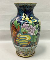 Front view of the vintage Chinese cloisonné enamel vase showing colorful floral and butterfly designs on a dark blue background.