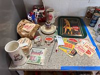 Photo showing the assorted items on a countertop including coasters, mugs, stirrers, ashtray, and Coca-Cola tray