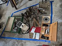 Overview photo showing all items including drill bits, Xacto set, plane cutters, jig and sharpener in an outlined blue area on a floor