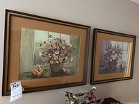 Two framed floral prints shown together on a wall above a sideboard, displaying the overall set.