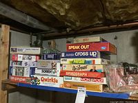 Stack of board games and puzzles on shelf under basement ceiling