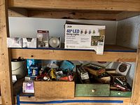 Wide view of wooden shelf containing various boxes of lightbulbs and miscellaneous hardware supplies.