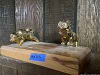 Photo of the two metal figurines, Mack Truck Bulldog on the right and Brockway Motor Company Wolf on the left, mounted on a wooden base with a measurement label 14x7x6.