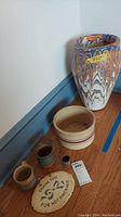Overall view of the multi-colored vase, Robinson Ransbottom bowl and smaller pottery pieces on hardwood floor.