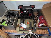 Lot overview showing all four power tools arranged on shelf including drill, saws, and jigsaw in cases and boxes.