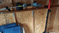 EGO battery operated trimmer ST1500F and its charger with battery on a wooden shelf in a shed environment.