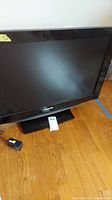 Front view of the Panasonic Viera LCD TV showing the screen, black bezel and stand, and power adapter on floor.