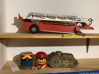Red fire truck with white ladder on top along with wooden soldier containers and tin tank