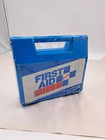 Blue plastic rectangular First Aid Kit case with handle, front labeled 'First Aid Only'.