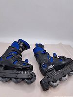 Pair of inline roller skates side view showing black and blue color, four wheels each, CCM branding on boot.