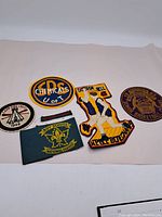 Six vintage sports cloth badges displayed on a white background showing various insignias and text