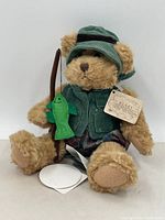 Front view of the plush teddy bear dressed in fishing attire holding a fishing pole with green felt fish.