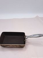 Photo showing the square skillet with dark cooking surface and metal handle.